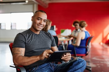 Confident male designer working on a digital tablet in red creative office space