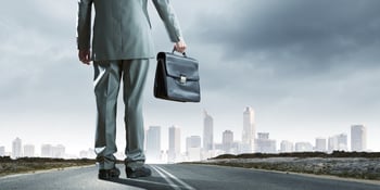 Back view of businessman on road with suitcase in hand