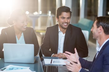 Businesswoman discussing with colleagues over laptop in office