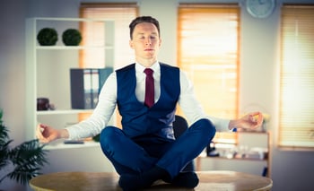 Calm businessman meditating in lotus pose in his office