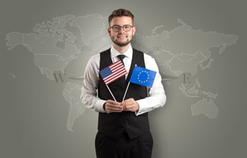 Cheerful businessman standing in front of a map with flag on his hand