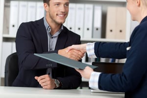Happy businessman shaking hands with a female interviewer in office-1