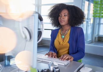 Portrait of a smiling woman at the computer in bright glass office, programmer,technology,AI