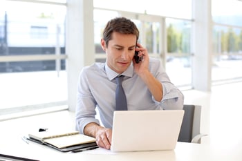 Portrait of businessman talking on mobile phone in office-1