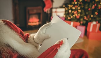 Santa claus writing list with a quill at home in the living room