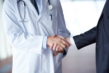 doctor handshake with a patient at doctors bright modern office in hospital