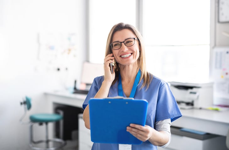 healthcare professional holding a blue clipboard while on the phone
