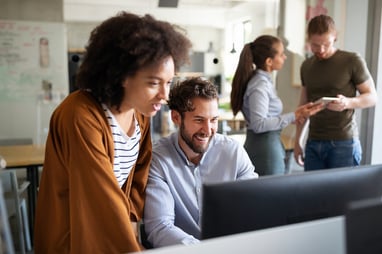 technology professionals collectively looking at a computer screen