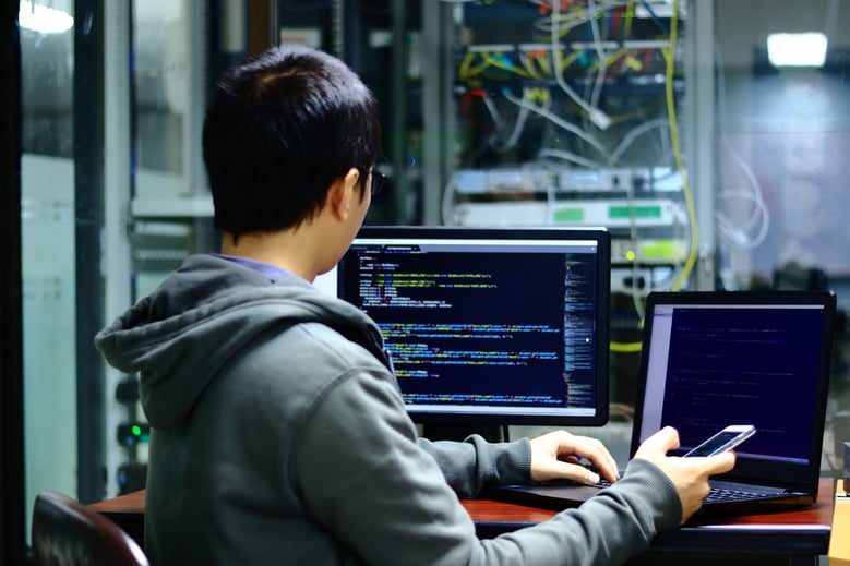 System analysts who are checking the validity of the developed application to connect to the database of computers and smartphones in front of the company's server room.