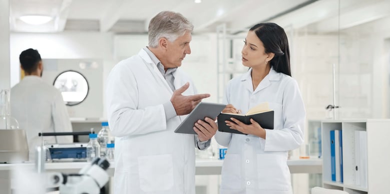 Two scientists in a lab holding tablets and having conversation. Functional Service Provider model.