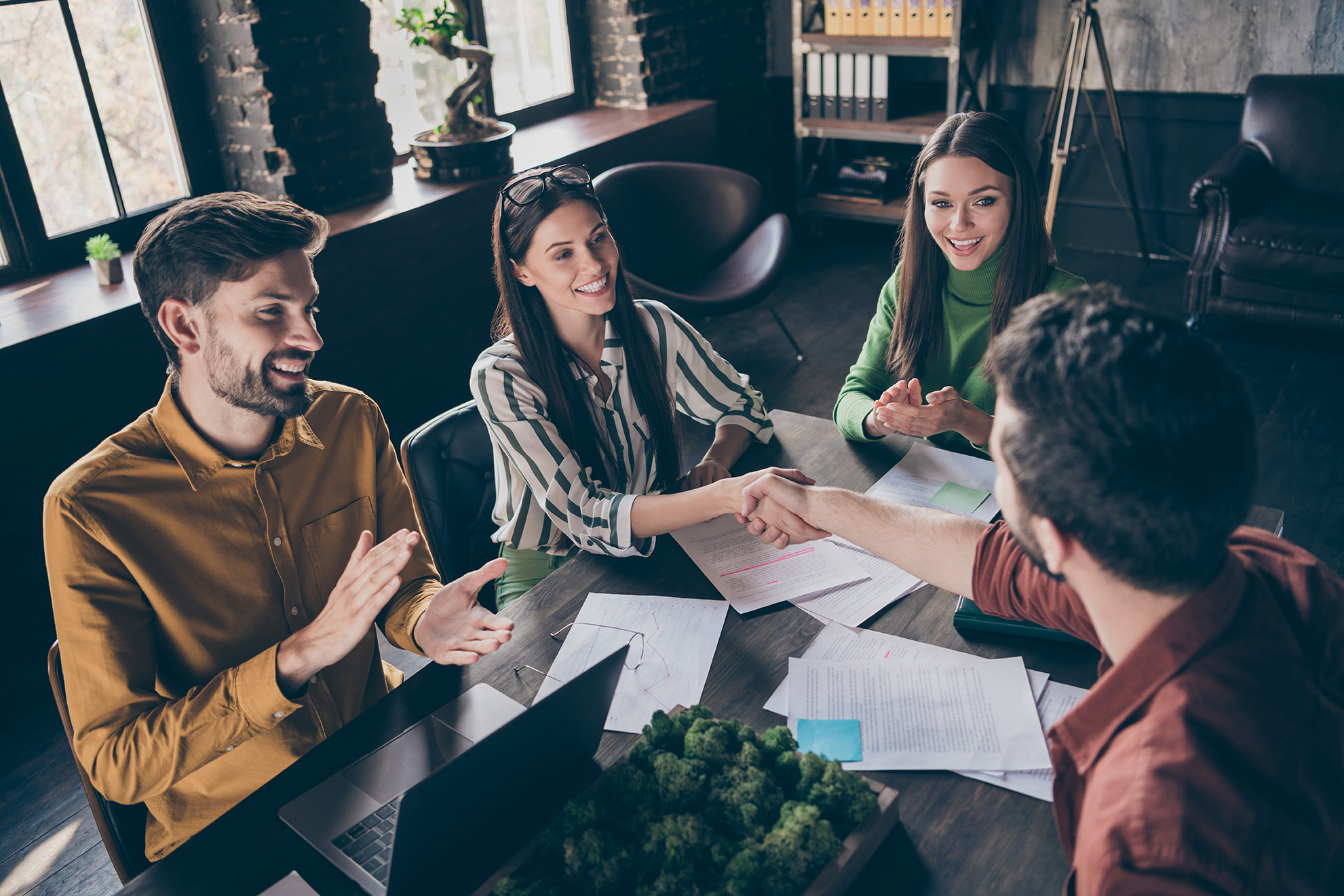 people shaking hands across an office table 