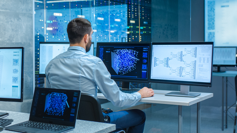 technologist coding in front of two monitors