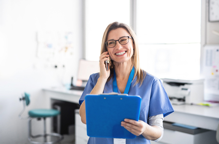 healthcare professional holding a blue clipboard while on the phone