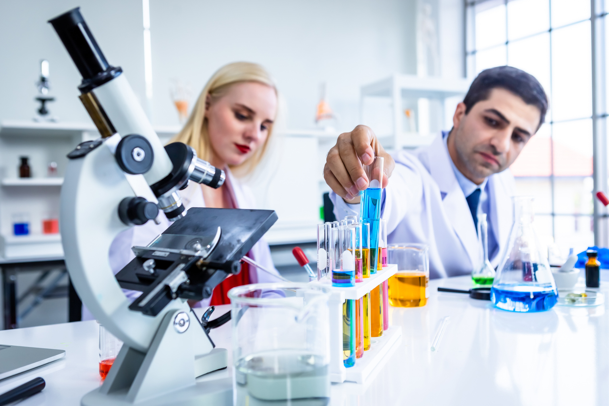 Two scientists examine a test tube sample in a chemistry lab during an investigation.